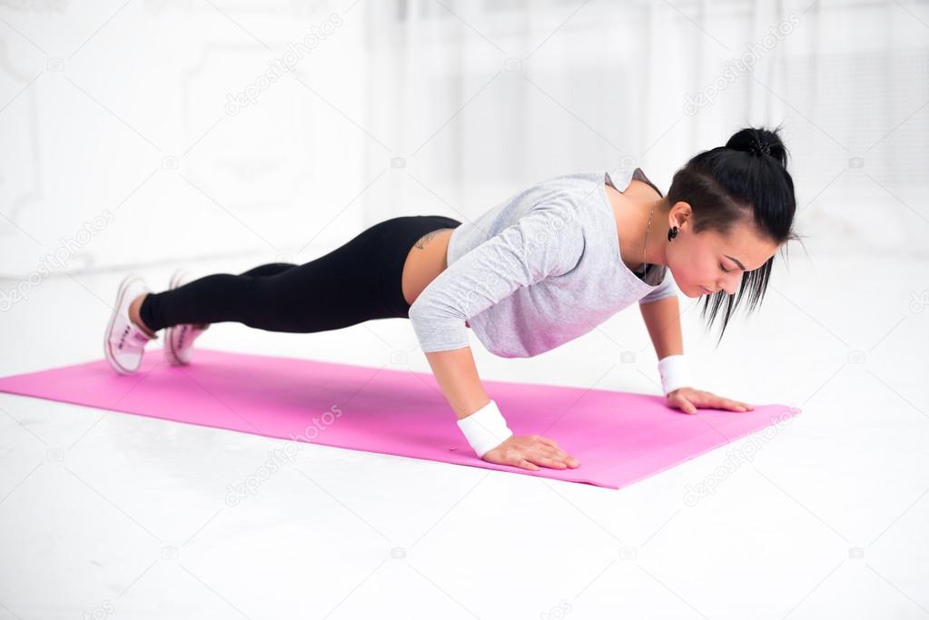 Young latin woman warming up and doing push ups at home fitness healthy lifestyle diet concept.