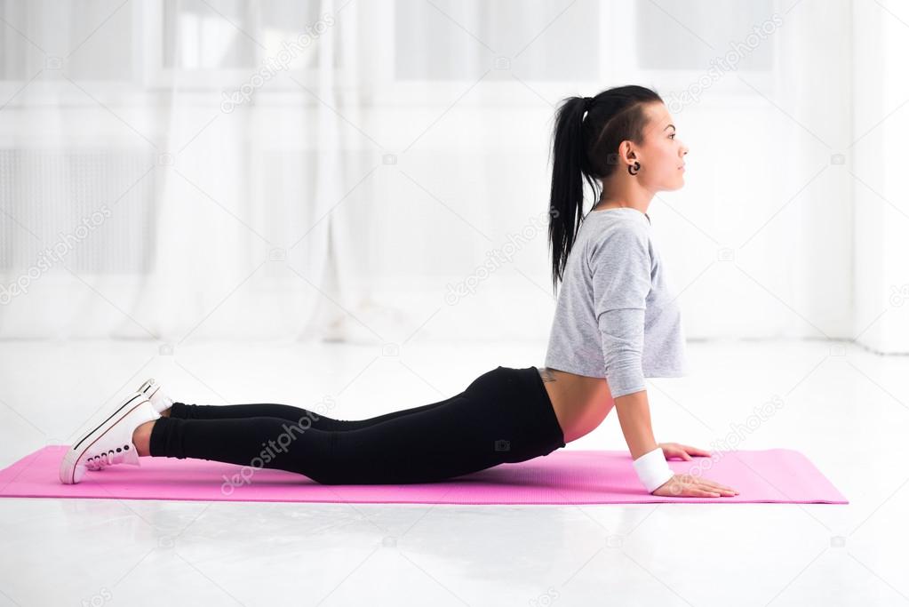 Girl doing warming up exercise for spine, backbend, arching stretching her back  working out at home or yoga class