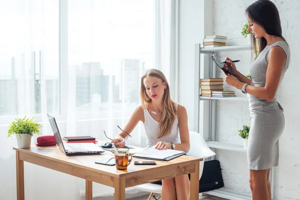 Zwei junge Frauen arbeiten zusammen im Büro Geschäftsfrau im ernsthaften Gespräch mit Kollegen. — Stockfoto