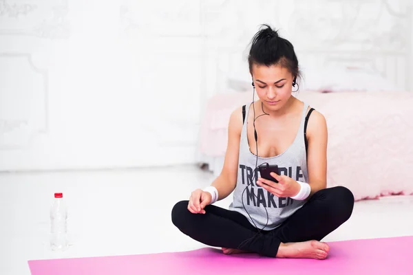 Frau mit Kopfhörer schaut nach dem Training entspannt auf Smartphone und hört Musik — Stockfoto