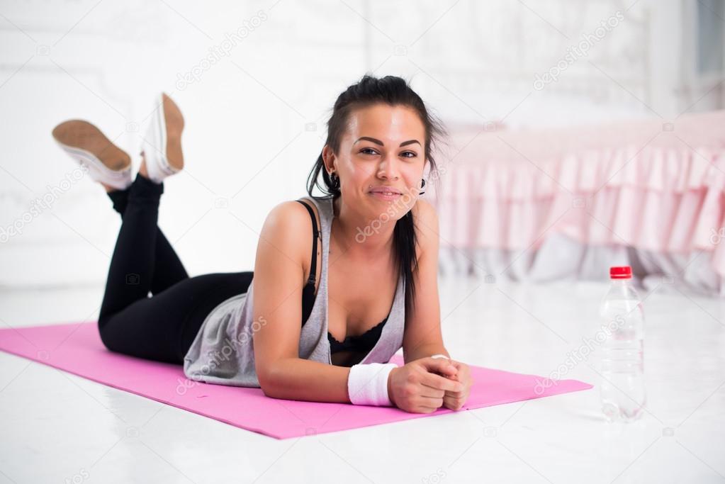 Young woman relaxing after workout at home lying on yoga mat concept healthy lifestyle, training, diet