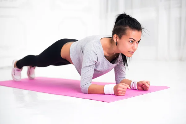 Спортивная стройная девочка делает упражнения на доске — стоковое фото