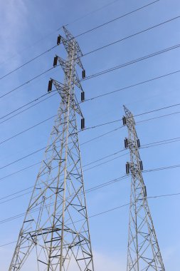 Mavi gökyüzü üzerinde yüksek gerilim direkleri.