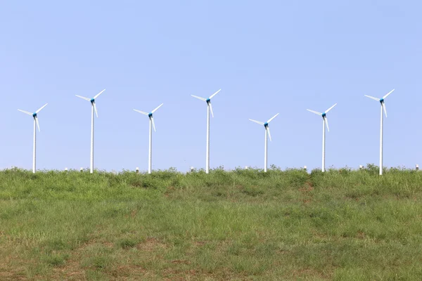 Blauwe lucht en wind turbine op groen gazon. — Stockfoto