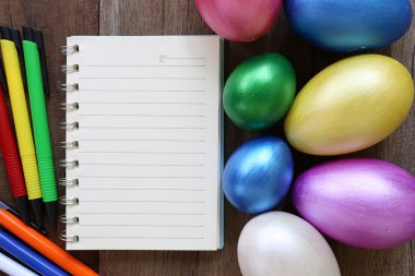 Paskalya yumurtaları ve ahşap zemin üzerine not defteri.