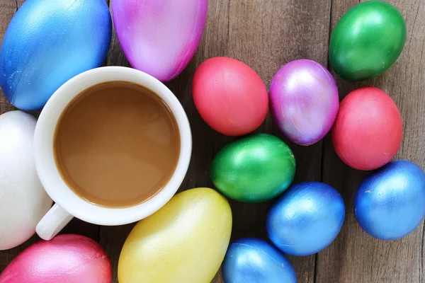 Ovos de Páscoa e xícara de café no fundo de madeira . — Fotografia de Stock