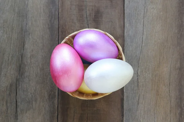 Ovos de Páscoa em uma cesta de vime em fundo de madeira . — Fotografia de Stock