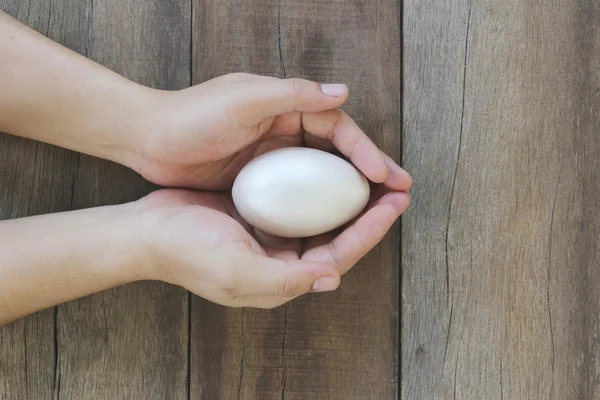 Uova di Pasqua in mano su fondo legno . — Foto Stock