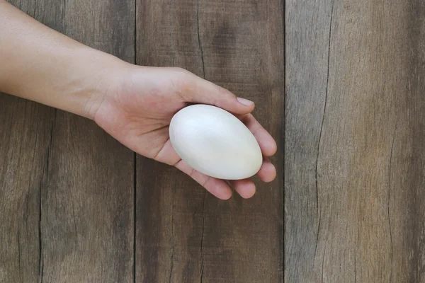 Huevos de Pascua en mano sobre fondo de madera . — Foto de Stock