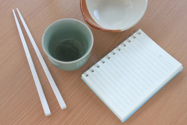 Tile bowl and white chopsticks wooden placed beside the book on — Stock Photo, Image