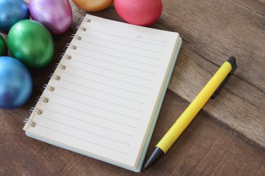 Paskalya yumurtaları ve ahşap zemin üzerine not defteri.