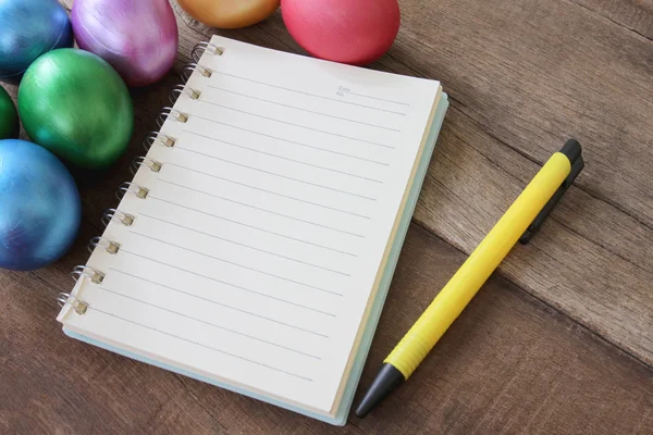 Paskalya yumurtaları ve ahşap zemin üzerine not defteri.