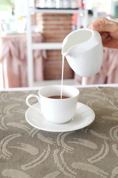 Women's hands are pouring milk from a white jug into a coffee cu — Stock Photo, Image