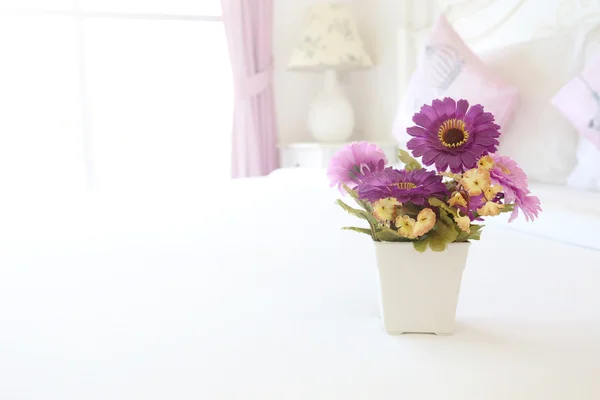 Vintage-rosa Kunstblumen auf einem Tisch im weißen Schlafzimmer. — Stockfoto