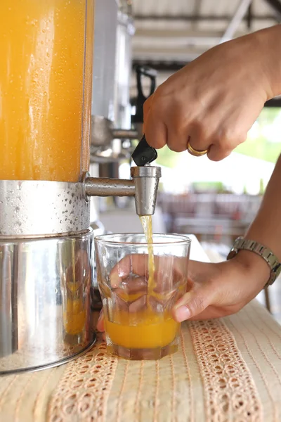 Vrouw handen waren het indrukken van sinaasappelsap in drankje glas. — Stockfoto