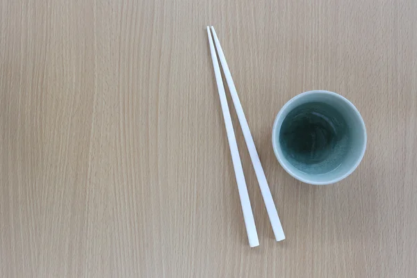 White chopsticks and cup in top view on wood background. — Stock Photo, Image