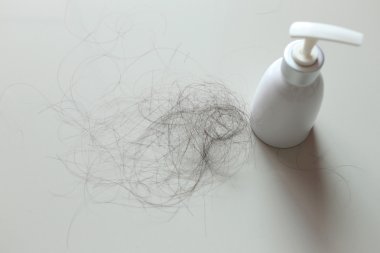 Şampuan ve saç dökülmesi beyaz kumaş üzerine beyaz şişe.