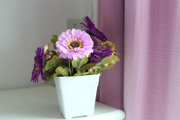 Фіолетові квіти штучні в білій вазі . — стокове фото