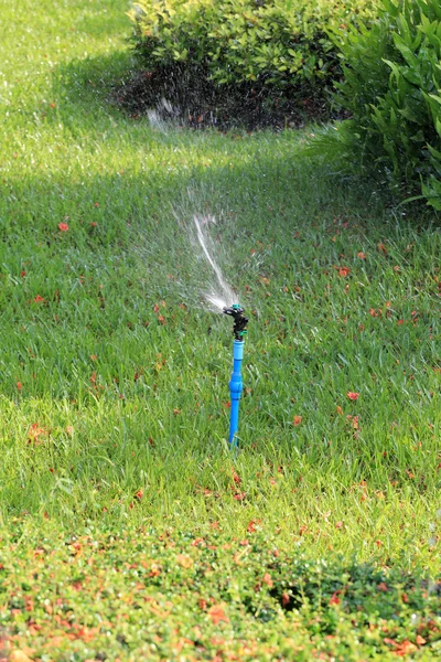 Springer is working and have water spread for green lawn. — Stock Photo, Image