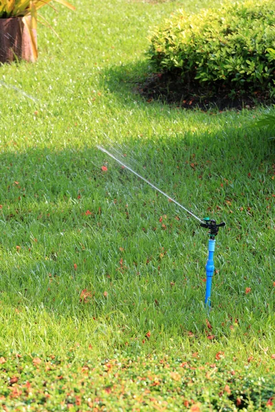 Springer is working and have water spread for green lawn. — Stock Photo, Image