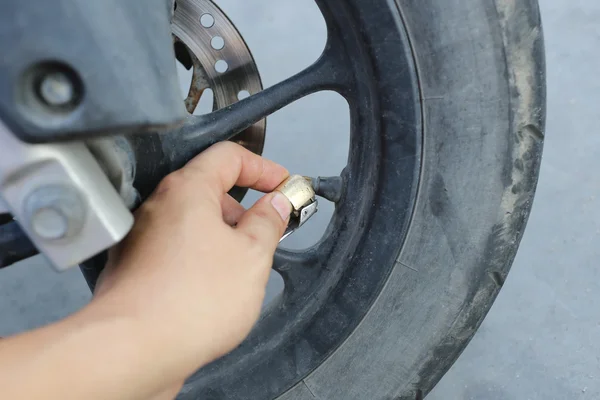 Main de l'homme remplir un vent dans les roues de la moto . — Photo