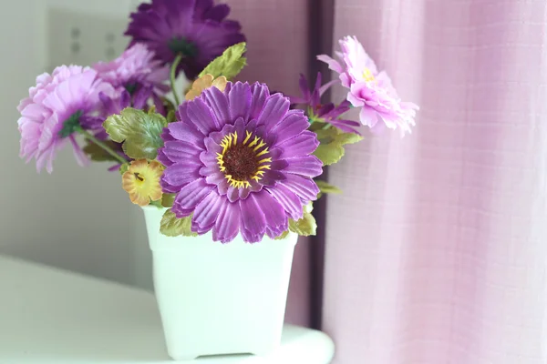 Lila Blüten künstlich in einer weißen Vase. — Stockfoto