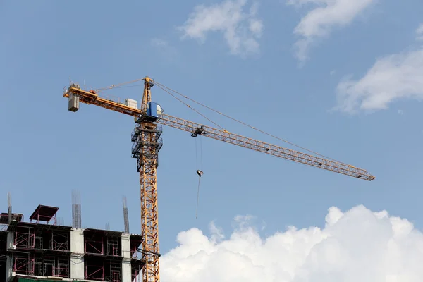 Guindaste que trabalha num edifício em construção durante o dia . — Fotografia de Stock