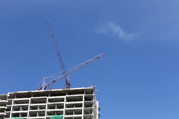 Guindaste que trabalha num edifício em construção durante o dia . — Fotografia de Stock