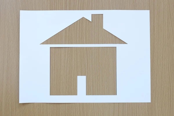 Paper shaped house on a background of brown wood. — Stock Photo, Image