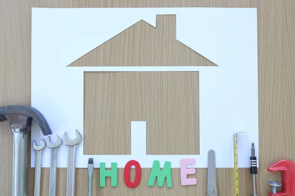 Paper shaped house on a background of brown wood and Craftsman t — Stock Photo, Image