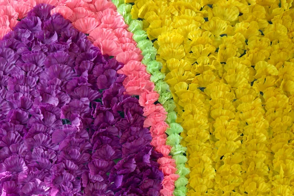 Achtergrond van kleurrijke nep bloemen die de achtergrond versierd. — Stockfoto
