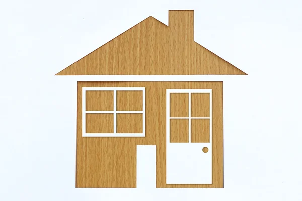 Paper shaped house on a background of brown wood. — Stock Photo, Image