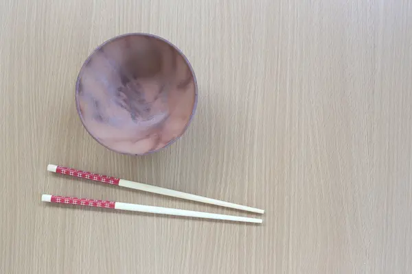 Wood chopsticks and brown bowl in top view on wood background. — Stock Photo, Image