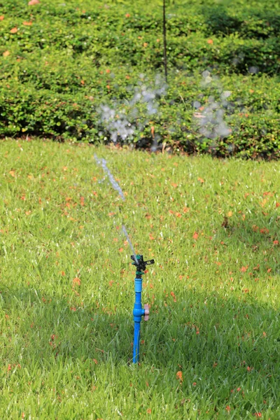 Springer is working and have water spread for green lawn. — Stock Photo, Image