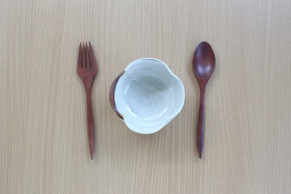 Wooden spoon,fork and white cup in top view on wood background. — Stock Photo, Image