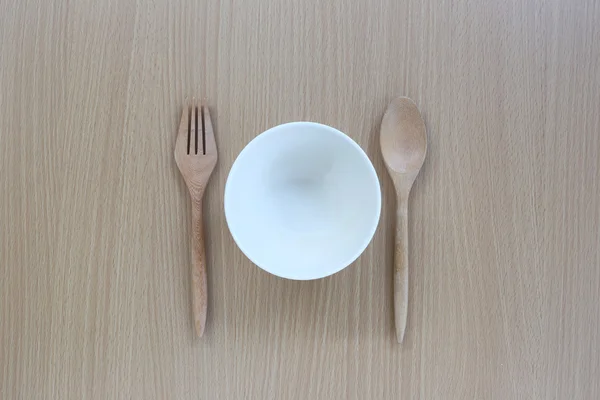 Houten lepel, vork en witte cup in bovenaanzicht op houten achtergrond. — Stockfoto