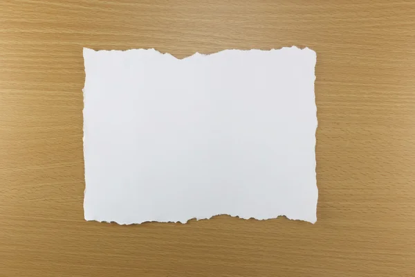 Weißer Papierriss auf braunem Holzhintergrund. — Stockfoto
