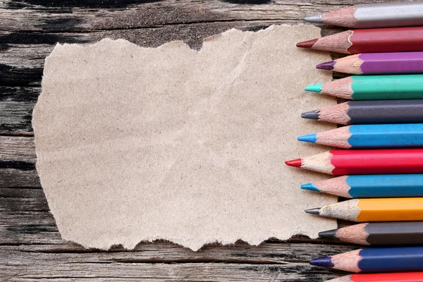 Zbliżenie kolor ołówki łączenie na brązowy papier i starym drewnianym tarasem — Zdjęcie stockowe