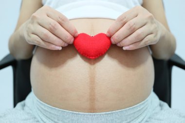 Kırmızı kalp sembol el Asyalı kadınlar hamile.