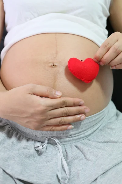 Czerwone serce symbol w ręku azjatyckich kobiet w ciąży. — Zdjęcie stockowe