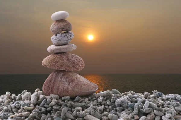 Баланс камня на свае скалы на фоне заката моря . — стоковое фото