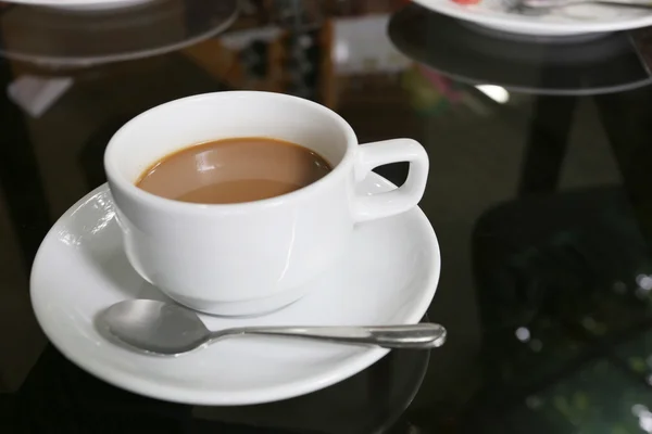 Valkoinen kahvikuppi sijoitettu elintarvikkeiden pöydälle . — kuvapankkivalokuva