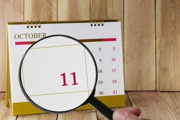 Увеличительное стекло в руке на календаре вы можете посмотреть одиннадцатую дату — стоковое фото