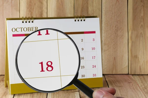 Увеличительное стекло в руке на календаре вы можете посмотреть восемнадцатый dat — стоковое фото