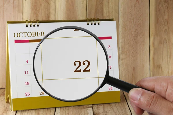 Увеличительное стекло в руке на календаре вы можете смотреть 22 dat — стоковое фото