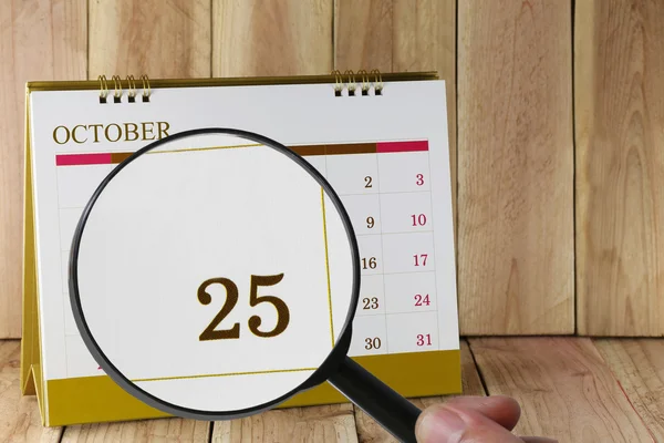 Увеличительное стекло в руке на календаре вы можете посмотреть двадцать пять да — стоковое фото