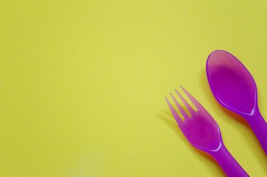 Plastik kaşık ve çatal parlak bir arkaplana yerleştirilir ve çalışmalarınızda tasarım için kopya alanı bulunur.