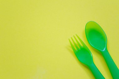 Plastik kaşık ve çatal parlak bir arkaplana yerleştirilir ve çalışmalarınızda tasarım için kopya alanı bulunur.