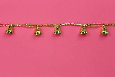 Kırmızı kağıttan arkaplanda Noel süslerinin altın zili ve Noel ve yeni yıl konseptinizde tasarım için bir kopya alanı.