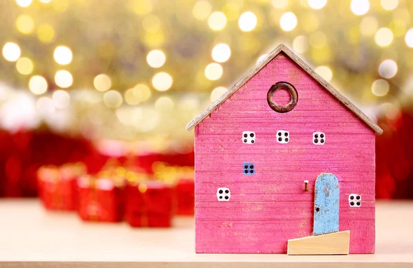 木造住宅はお祝いのクリスマスと新年のデザインのための赤いギフトボックスの近くに配置されます — ストック写真